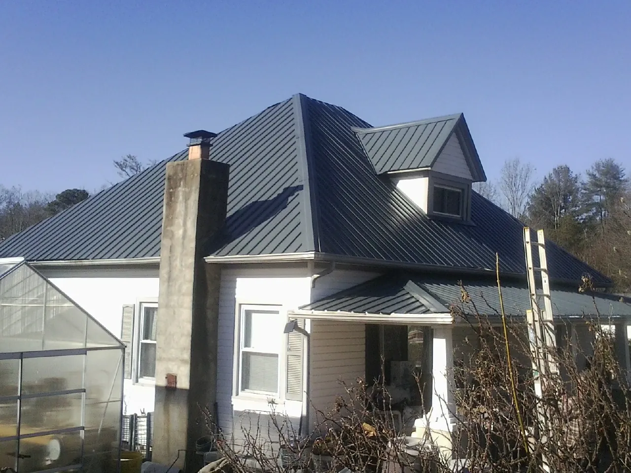 Dark blue standing seam metal roof on a white farmhouse with dormer — Slate & Tile Roof Repair by Roofing Brothers in Stirling
