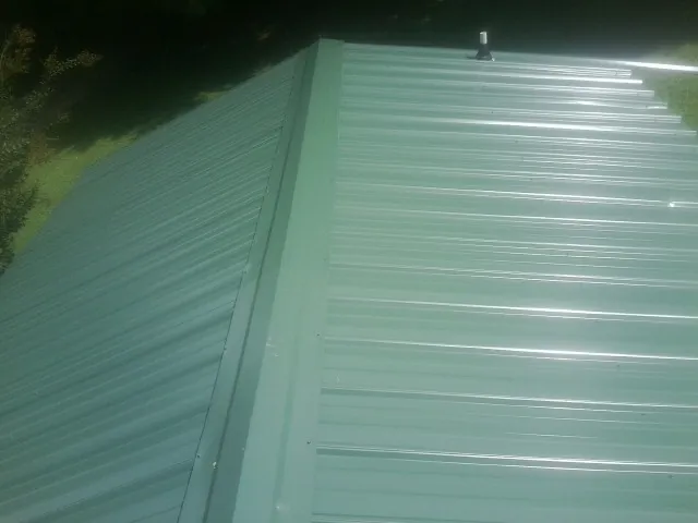 New green metal panels meeting at the ridge of a roof — Flat Roof Repair work by our crew in Stirling