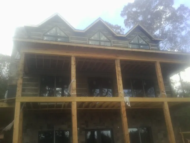 Dormers and porch framing on a large log home under construction — Roof Coating work by our crew in Stirling