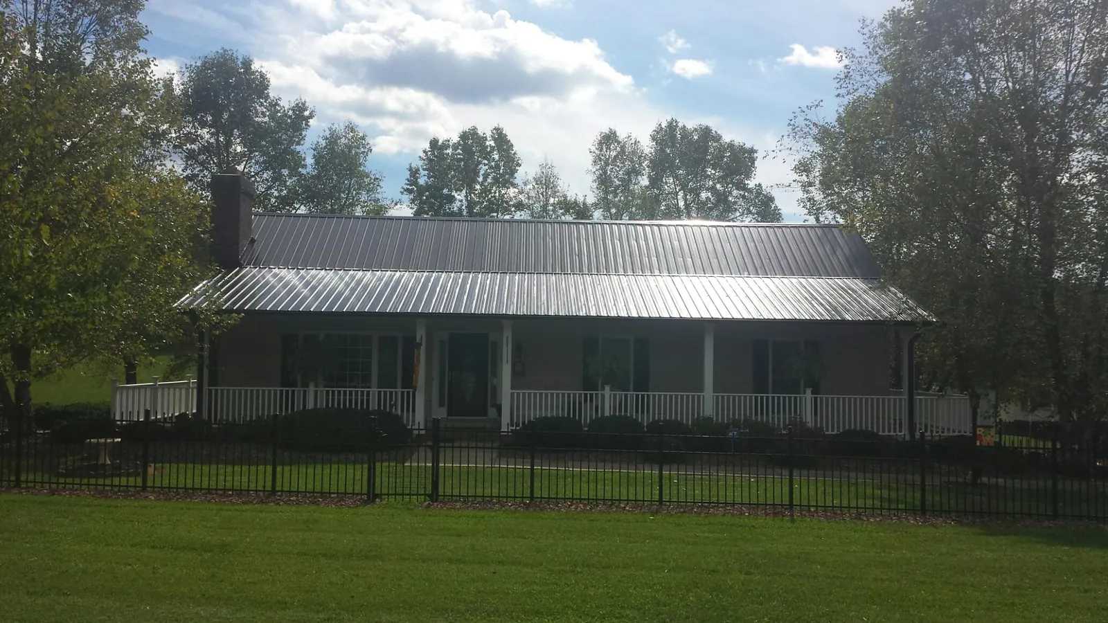 Gray metal roof on a brick ranch with a full width front porch — Gutter Guard Installation work by our crew in Stirling