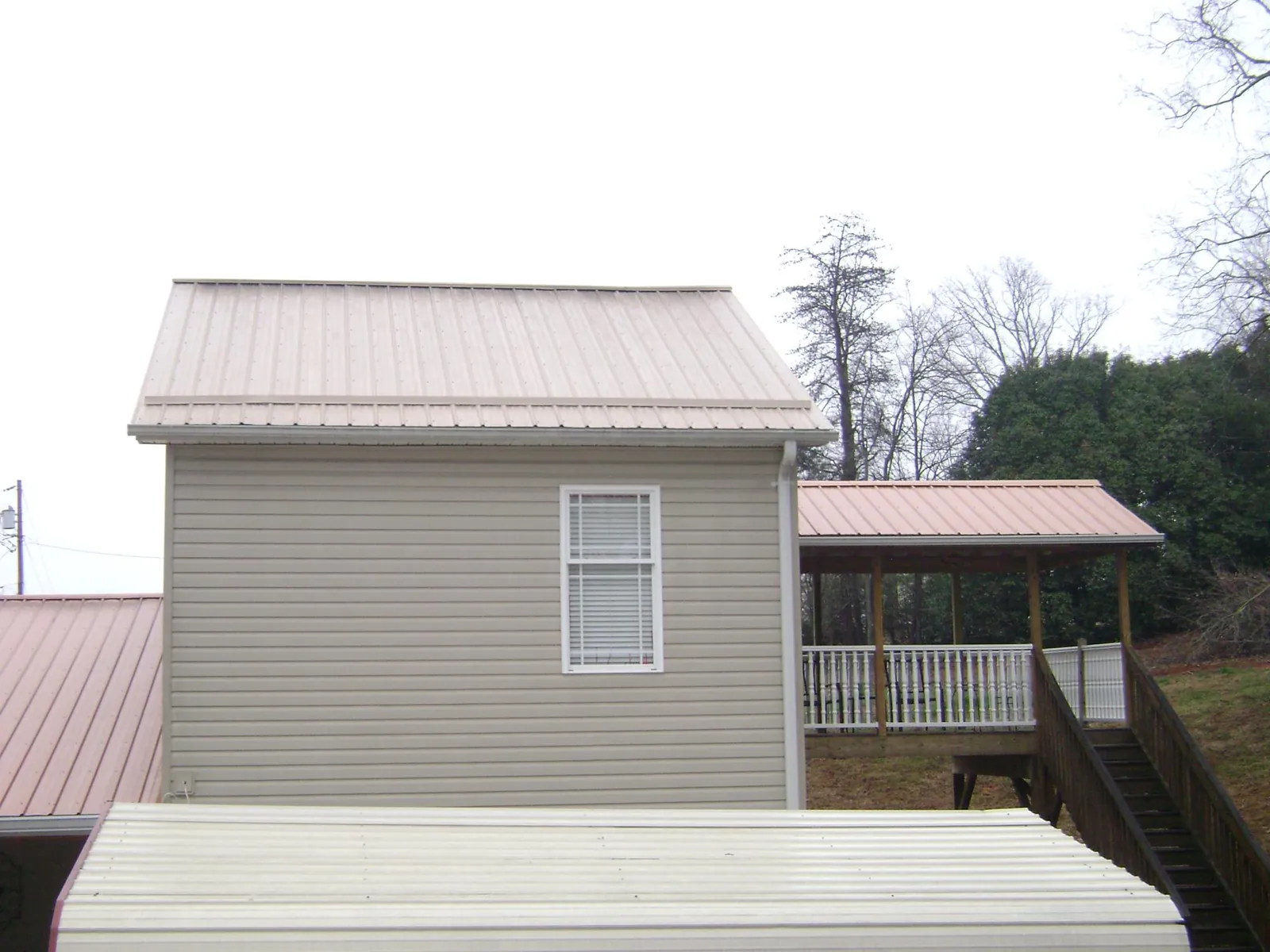 Tan metal roofs on a two story addition and attached porch, from a Roof Replacement job in Stirling