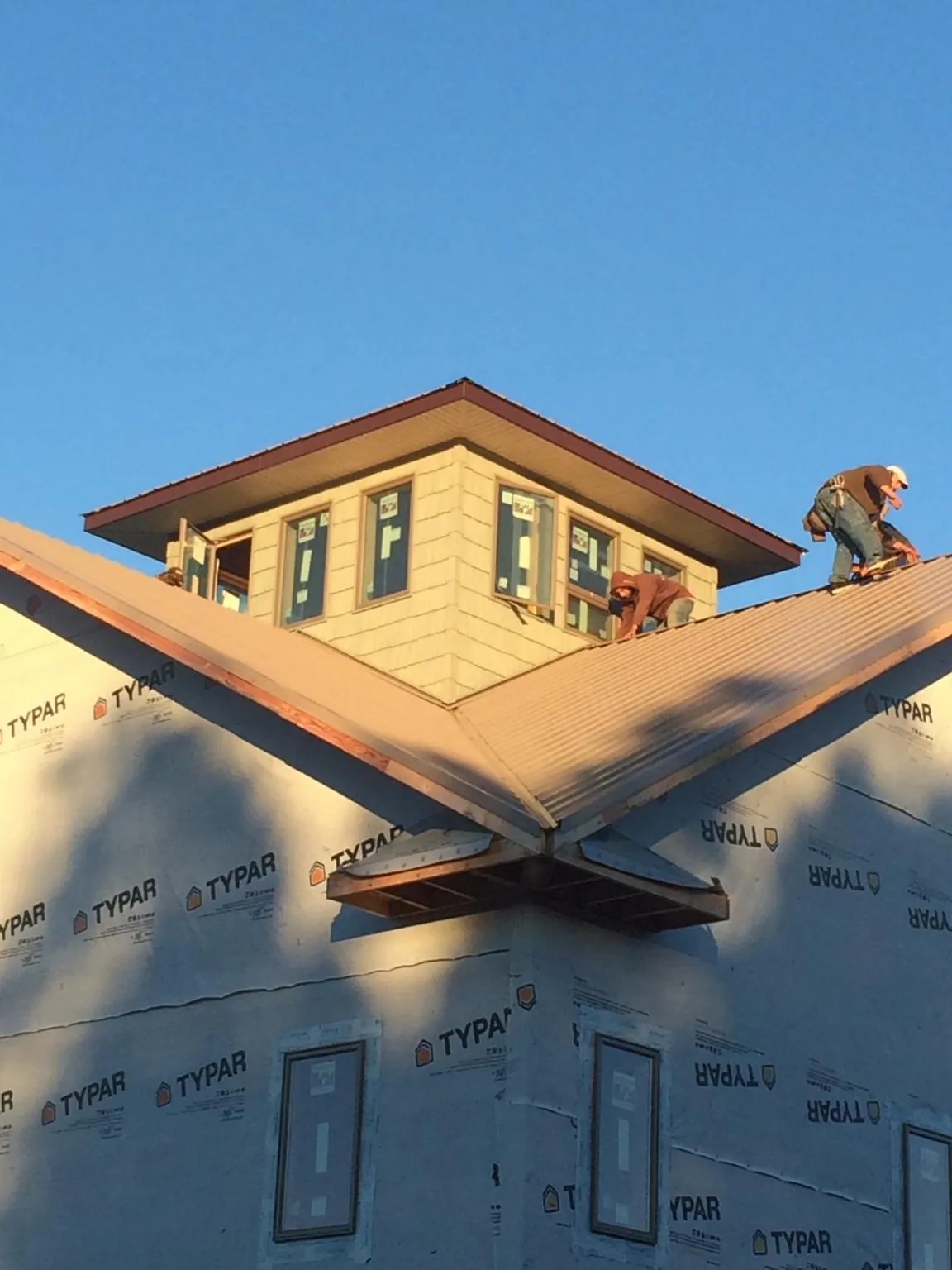 Roofers working around a rooftop cupola on a new metal roof at sunset — Roof Waterproofing in Stirling by Roofing Brothers